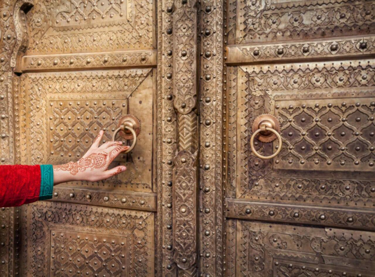 Henna-verzierte Hand klopft mit Türklopfer an Tür